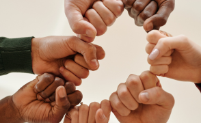 fist bump of 7 different people of varied skin tones.